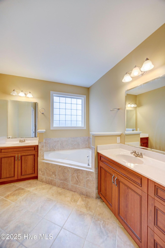 full bath featuring tile patterned flooring, two vanities, a sink, and a bath