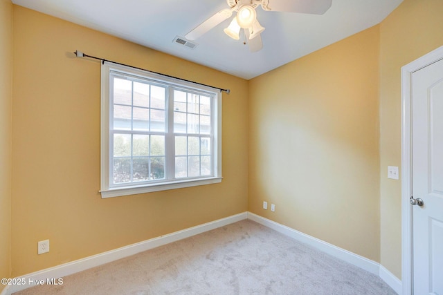 carpeted spare room with ceiling fan, visible vents, and baseboards