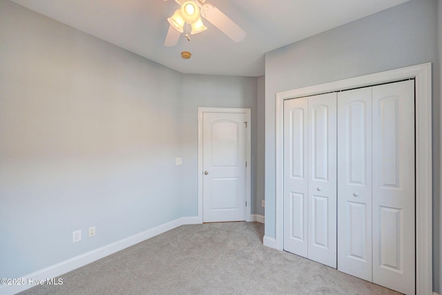 unfurnished bedroom with a closet, light carpet, ceiling fan, and baseboards