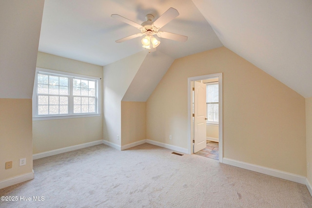 additional living space with visible vents, baseboards, ceiling fan, carpet, and vaulted ceiling