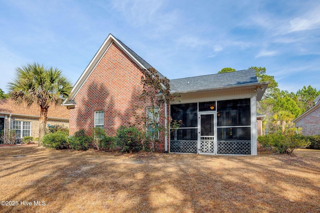 rear view of property featuring a sunroom and brick siding