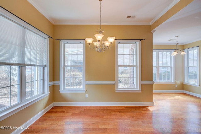 unfurnished dining area featuring light wood-style floors, visible vents, crown molding, and an inviting chandelier