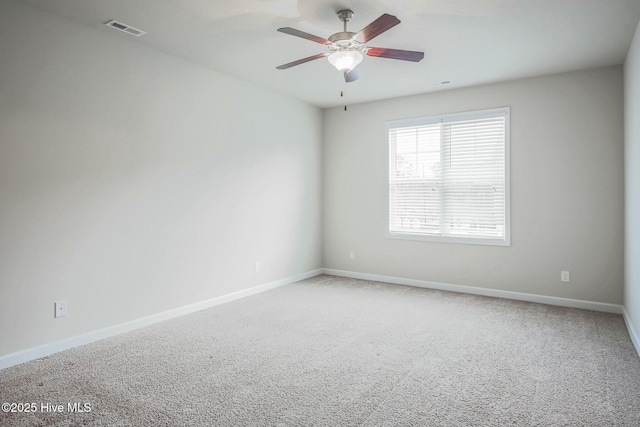 carpeted spare room featuring visible vents, a ceiling fan, and baseboards