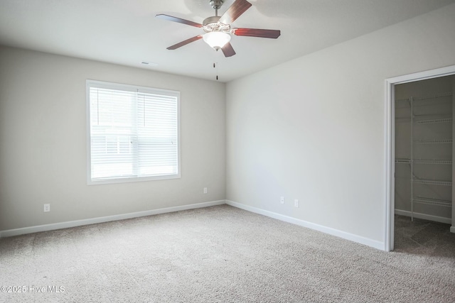 carpeted spare room with ceiling fan and baseboards