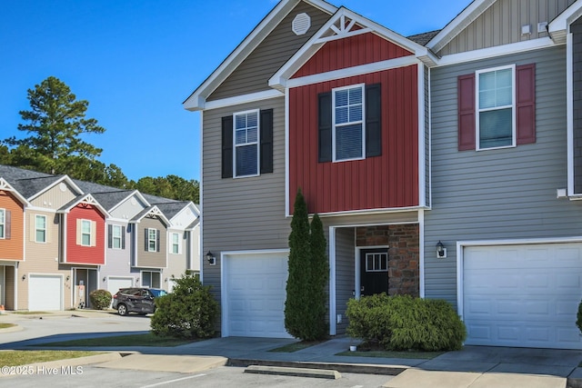 view of front of home featuring an attached garage, stone siding, board and batten siding, concrete driveway, and a residential view