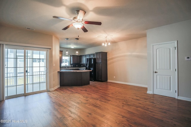 kitchen featuring baseboards, freestanding refrigerator, dark wood-style floors, open floor plan, and dark brown cabinetry