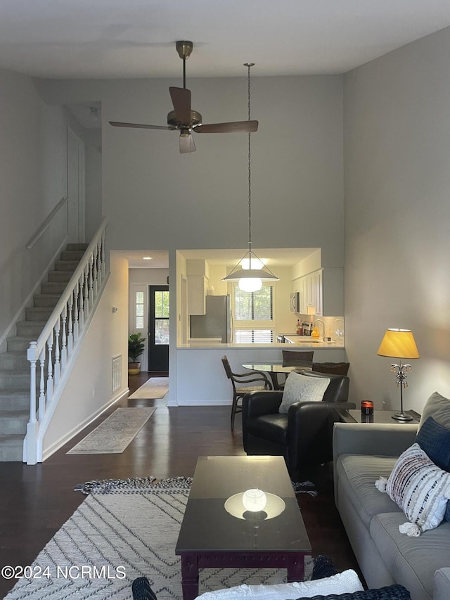 living area featuring visible vents, stairs, a high ceiling, and dark wood-style flooring