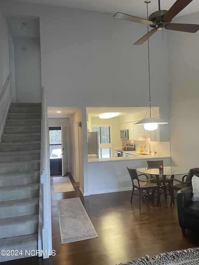 interior space with a towering ceiling, stairs, baseboards, and dark wood-style flooring