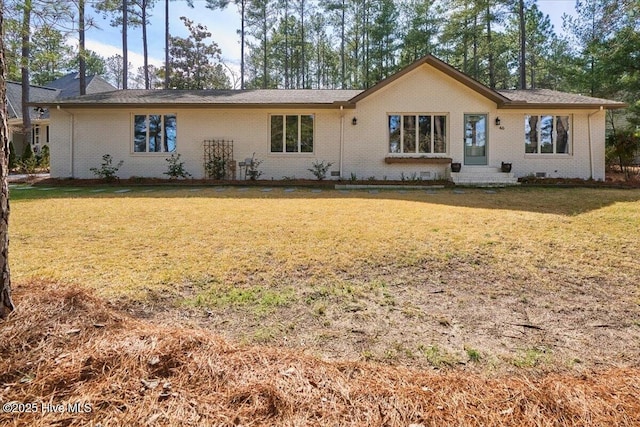 rear view of house featuring crawl space, brick siding, and a yard