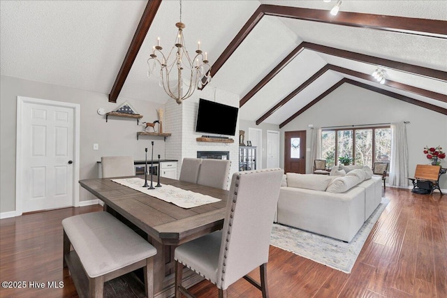 dining space with dark wood-style floors, a fireplace, beam ceiling, and a textured ceiling