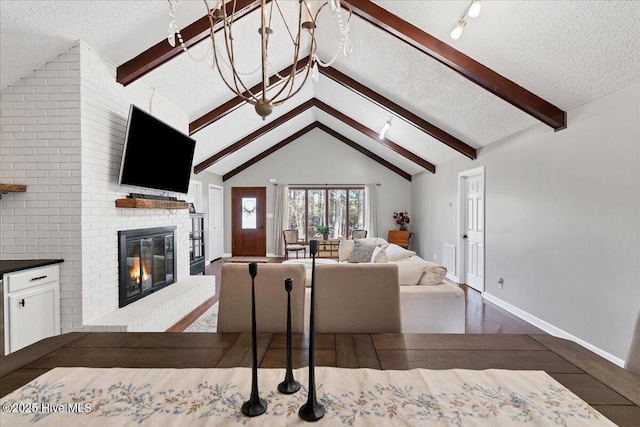 living room featuring vaulted ceiling with beams, a textured ceiling, a brick fireplace, and baseboards