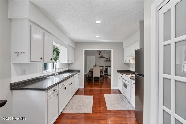 kitchen with electric stove, dark wood-style flooring, dark countertops, white cabinets, and a sink