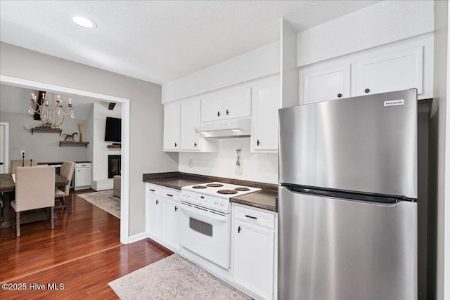 kitchen with under cabinet range hood, white cabinets, electric stove, freestanding refrigerator, and dark wood finished floors