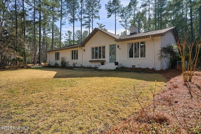 view of front facade featuring crawl space, a front yard, a chimney, and brick siding