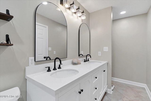 full bath with double vanity, recessed lighting, a sink, and baseboards