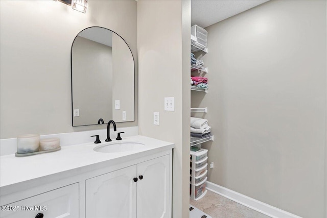 bathroom featuring a closet, vanity, and baseboards