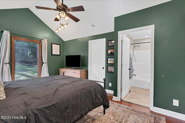 bedroom featuring lofted ceiling, ensuite bath, light wood-style flooring, and baseboards