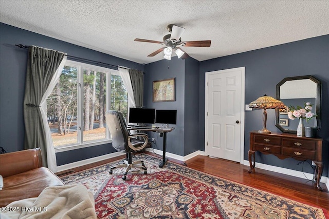 home office with a textured ceiling, dark wood-style flooring, a ceiling fan, and baseboards