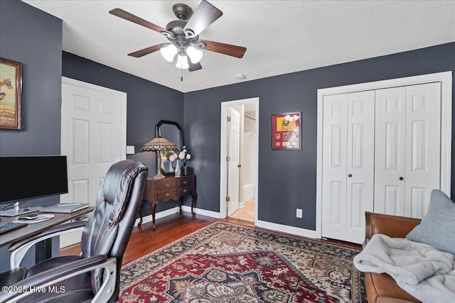 office space featuring dark wood-style floors, a textured ceiling, a ceiling fan, and baseboards