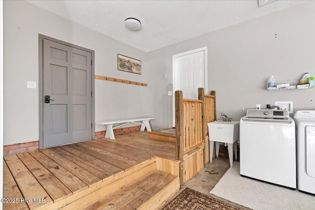 washroom featuring light wood-style floors, washing machine and dryer, a sink, a textured ceiling, and laundry area