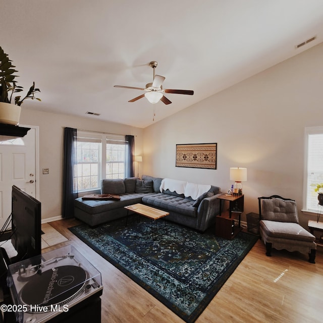 living room with lofted ceiling, ceiling fan, baseboards, and wood finished floors