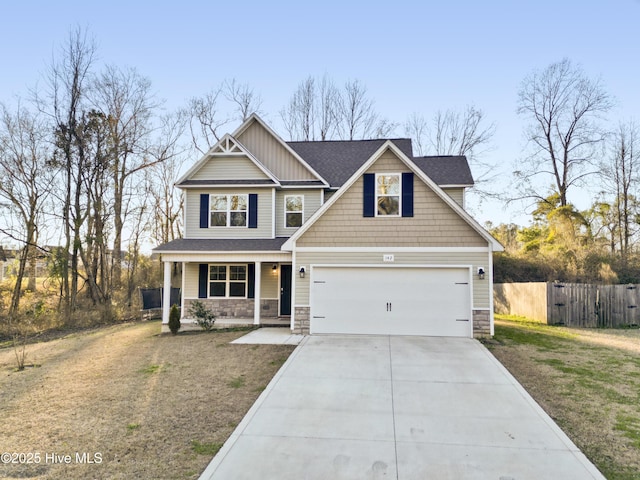 craftsman house featuring fence, driveway, stone siding, board and batten siding, and a porch