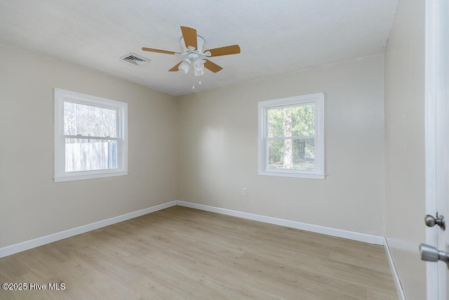 empty room featuring a ceiling fan, light wood-type flooring, visible vents, and baseboards