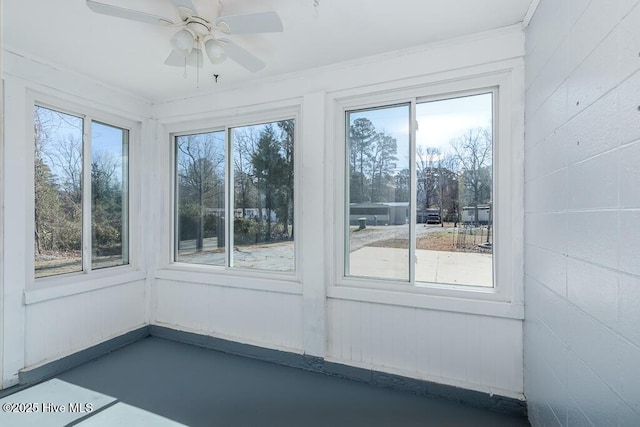 unfurnished sunroom featuring a ceiling fan and a healthy amount of sunlight