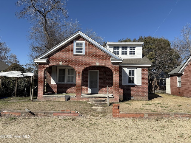 bungalow-style house featuring brick siding, a front lawn, and roof with shingles