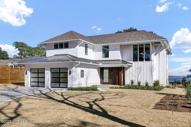 modern farmhouse style home featuring driveway, metal roof, roof with shingles, a standing seam roof, and fence