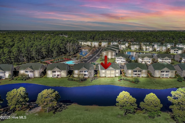 aerial view at dusk featuring a water view and a residential view