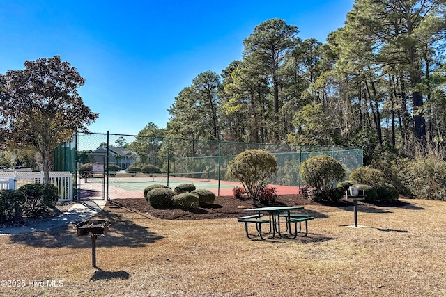 view of property's community with a tennis court and fence