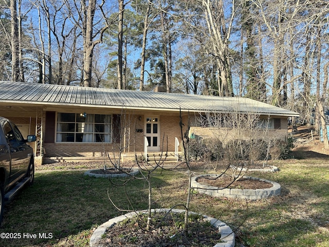 view of front of property with brick siding, metal roof, and a front lawn