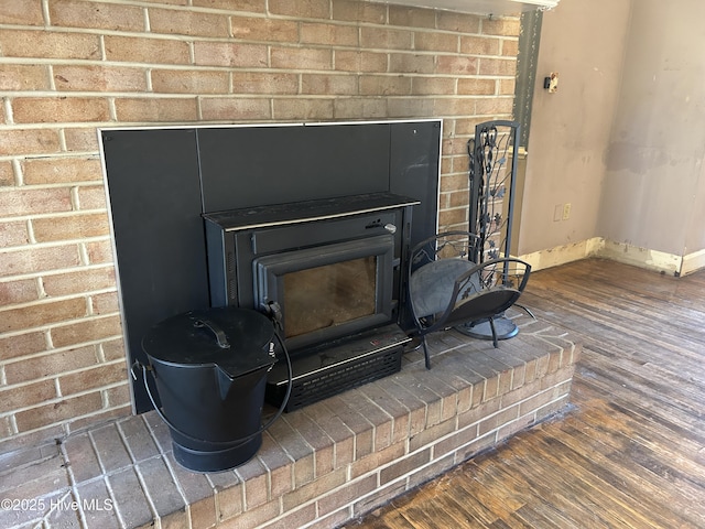 room details featuring a wood stove, baseboards, and wood finished floors