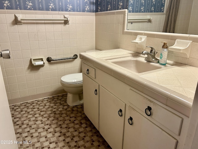 full bath with toilet, wallpapered walls, tile walls, and a wainscoted wall