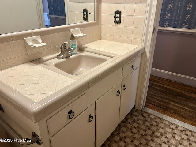 bathroom featuring backsplash, vanity, and baseboards