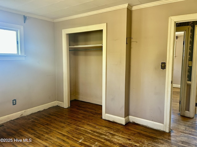 unfurnished bedroom with dark wood-style floors, ornamental molding, a closet, and baseboards