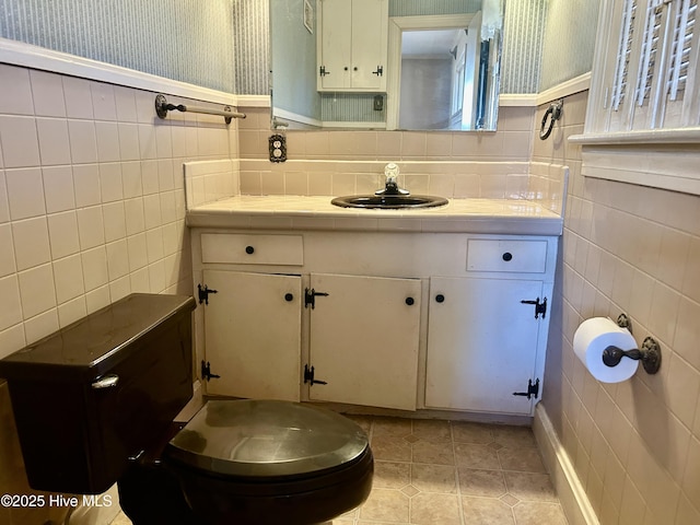 bathroom featuring tile patterned flooring, vanity, tile walls, and wallpapered walls