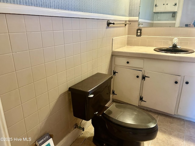 bathroom featuring a wainscoted wall, tile walls, toilet, tile patterned flooring, and wallpapered walls