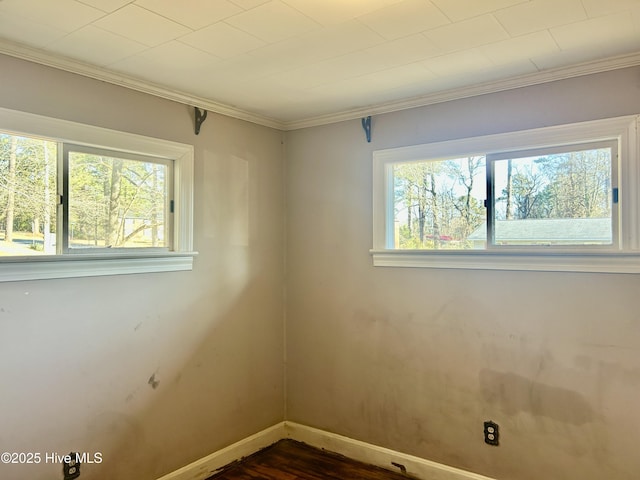 spare room with baseboards, dark wood finished floors, and crown molding