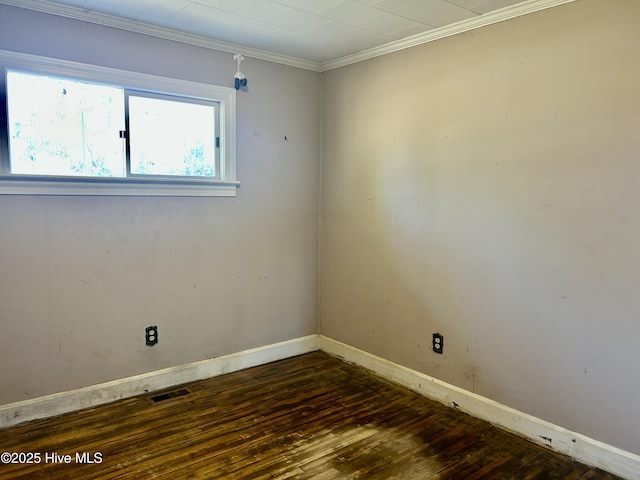 spare room featuring dark wood-style flooring, visible vents, crown molding, and baseboards