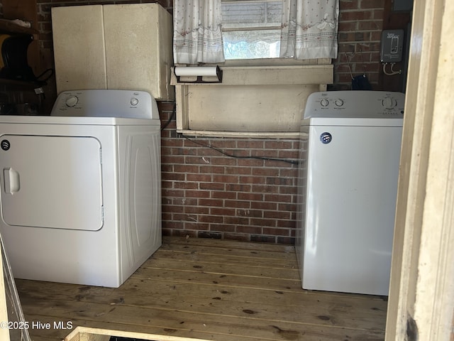 laundry area with washer and dryer, laundry area, and brick wall