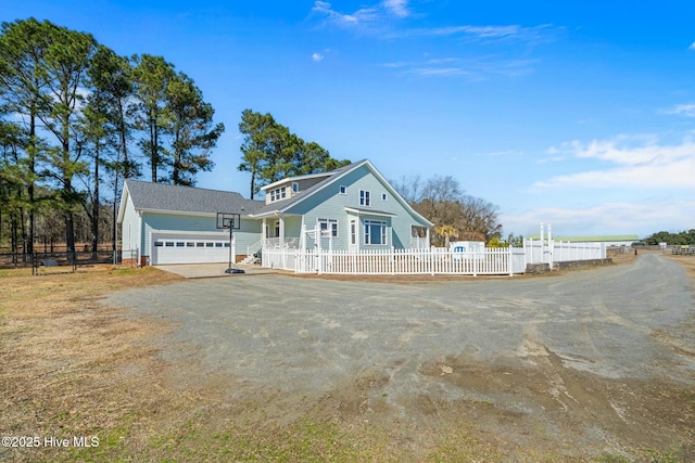 view of front of home with driveway, a fenced front yard, and an attached garage