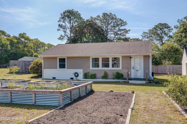 view of front of home featuring fence, a shingled roof, a vegetable garden, and a front yard