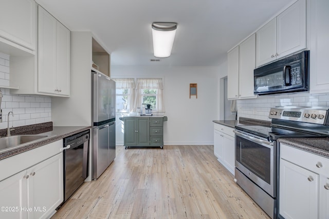 kitchen with a sink, light wood-style flooring, decorative backsplash, and black appliances