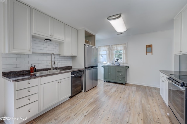 kitchen with a sink, stainless steel appliances, visible vents, light wood finished floors, and decorative backsplash