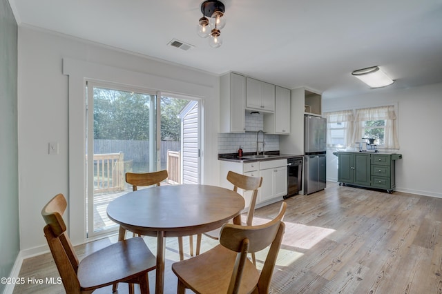 dining room with baseboards, light wood-style flooring, and visible vents
