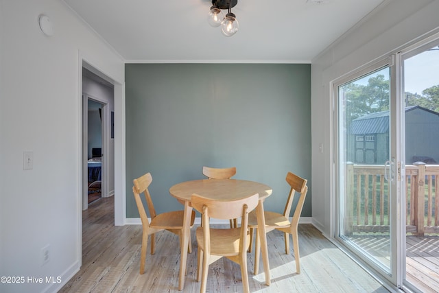 dining room with ornamental molding, baseboards, and light wood-style floors