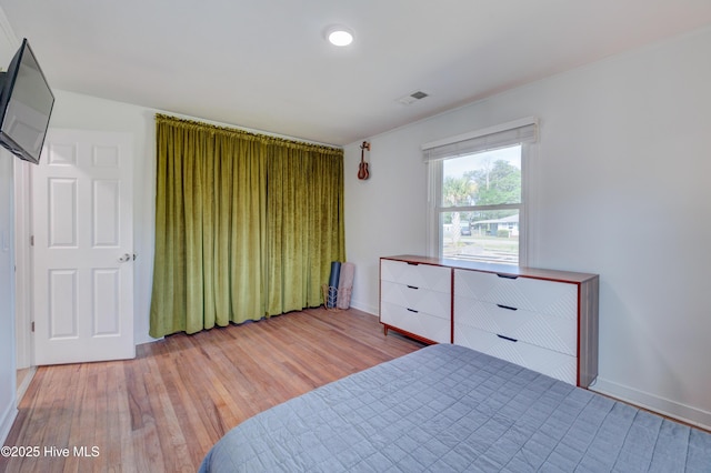 bedroom featuring light wood finished floors, baseboards, and visible vents