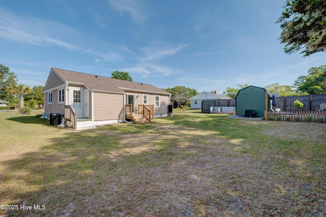 rear view of property with a yard, an outdoor structure, fence, and a storage unit